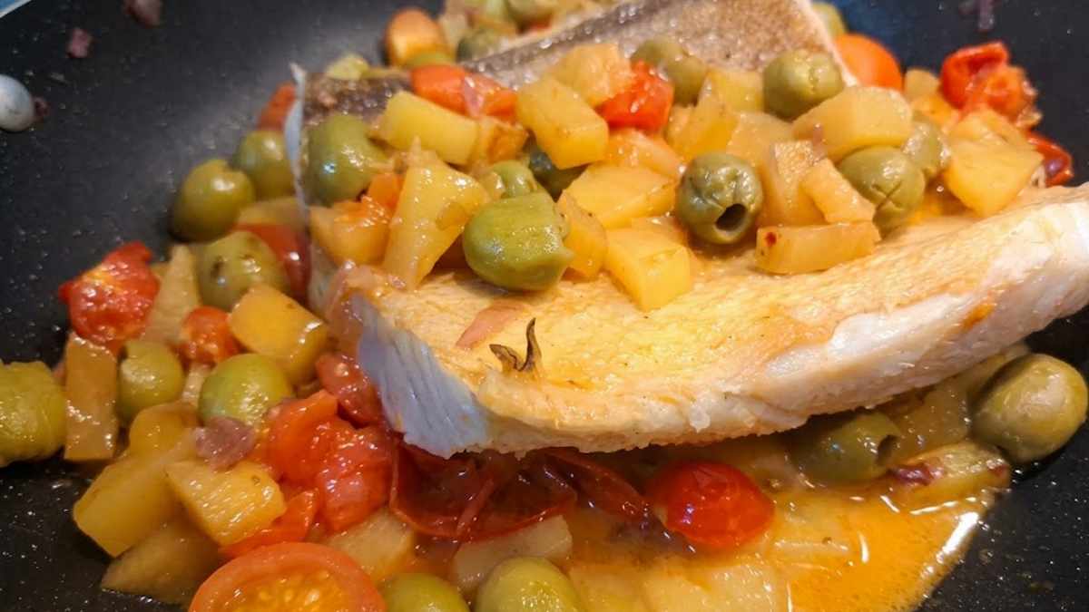 Cottura in padella dello stoccafisso con patate, olive e pomodorini. Il filetto di stocco appare rigenerato e morbido grazie al processo di ammollo in acqua locale.