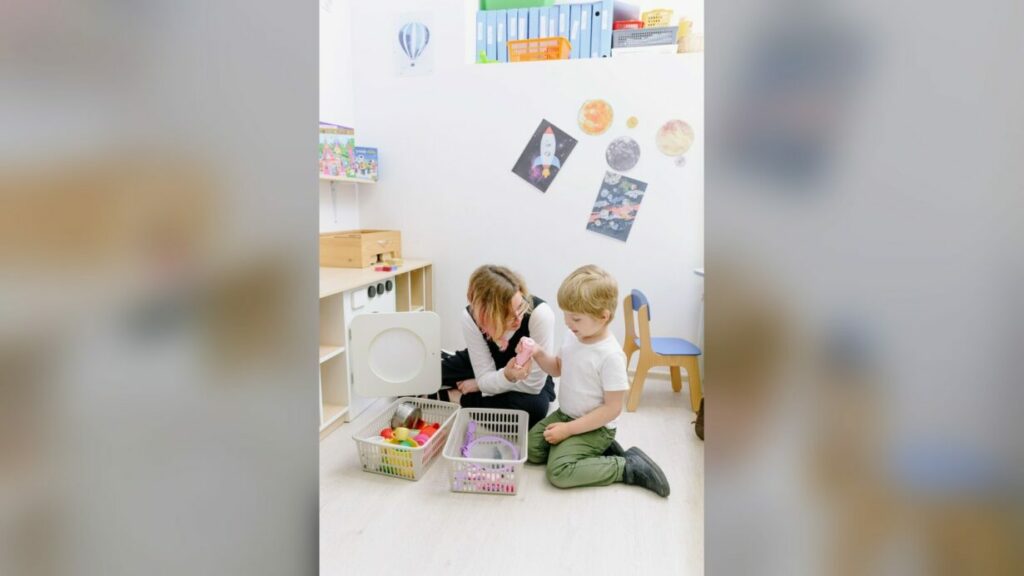 Educatrice gioca con un bambino in un asilo nido