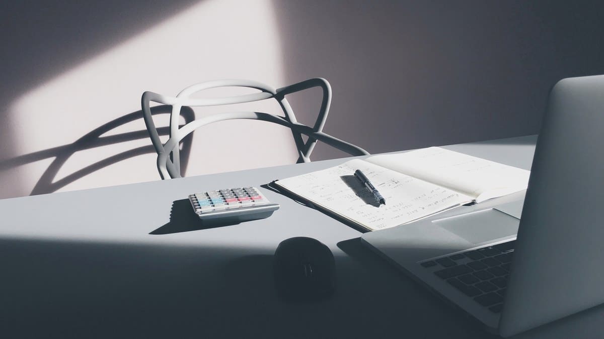 Scrivania con computer portatile calcolatrice e quaderno aperto