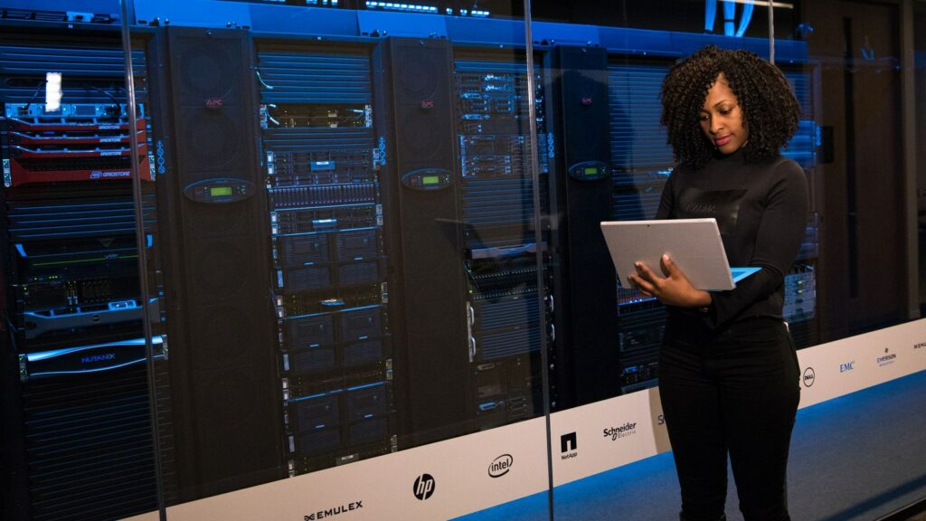 Professionista con un computer portatile davanti agli armadi di una sala server