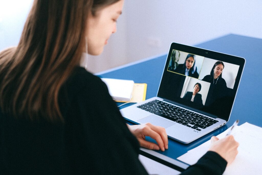Persona davanti a una videoconferenza su laptop, immagine illustrativa per deepfake e frodi digitali