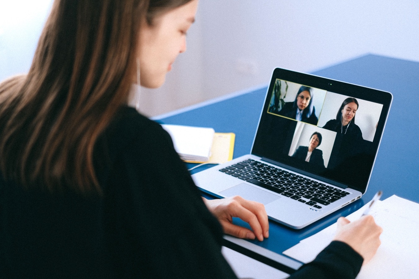 Persona davanti a una videoconferenza su laptop, immagine illustrativa per deepfake e frodi digitali