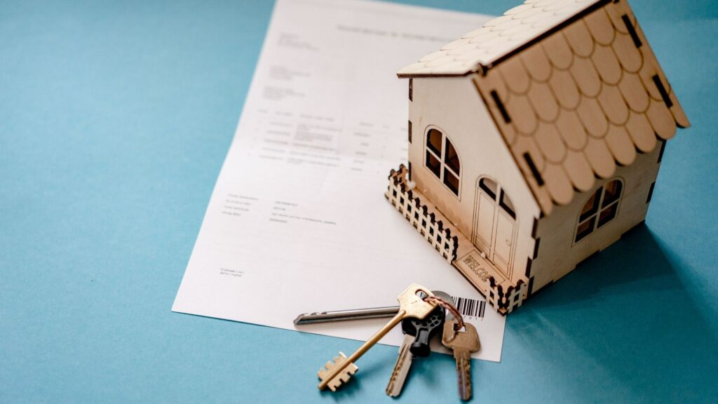 Modellino di una casa con chiavi e documento appoggiati sul tavolo