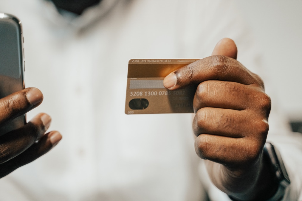 Mani che tengono uno smartphone e una carta bancaria per un pagamento online