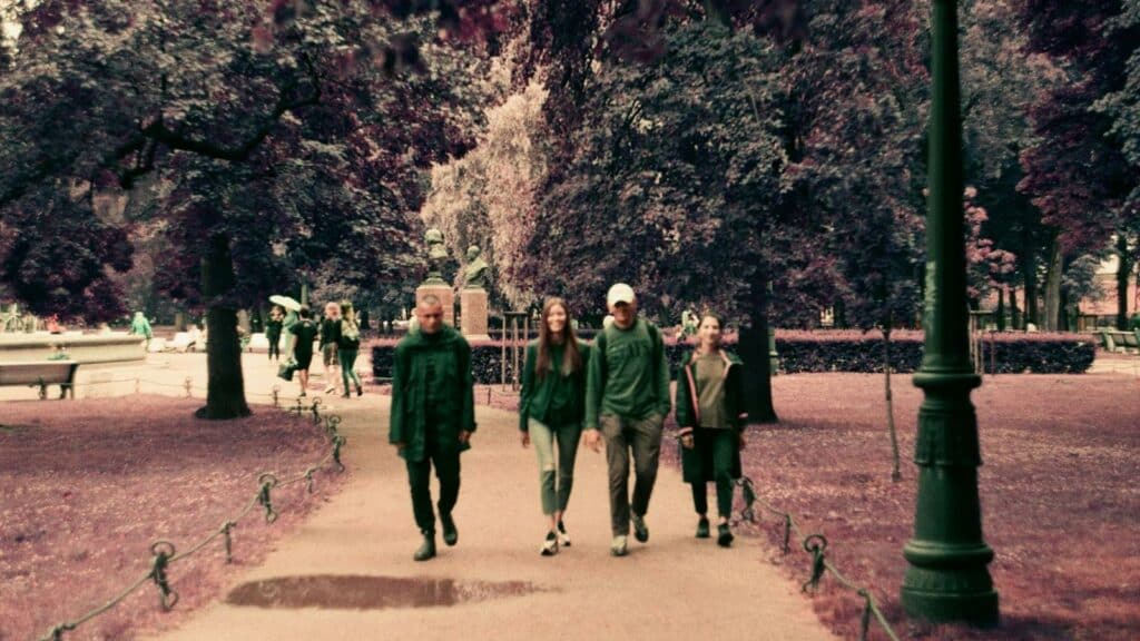 Un gruppo di persone cammina lungo un viale alberato in un parco.