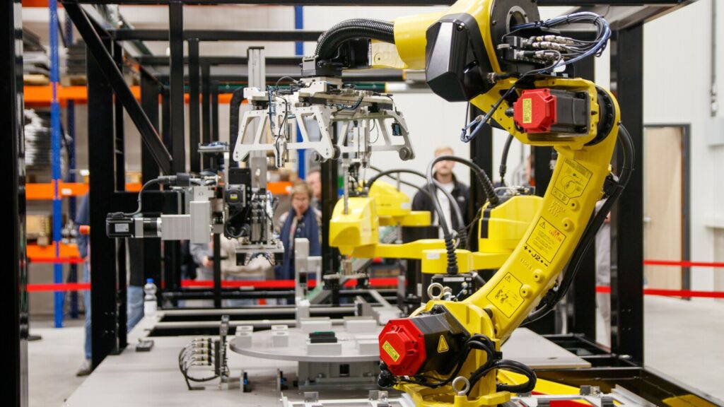 Braccio robotico industriale giallo in una linea di produzione automatizzata.
