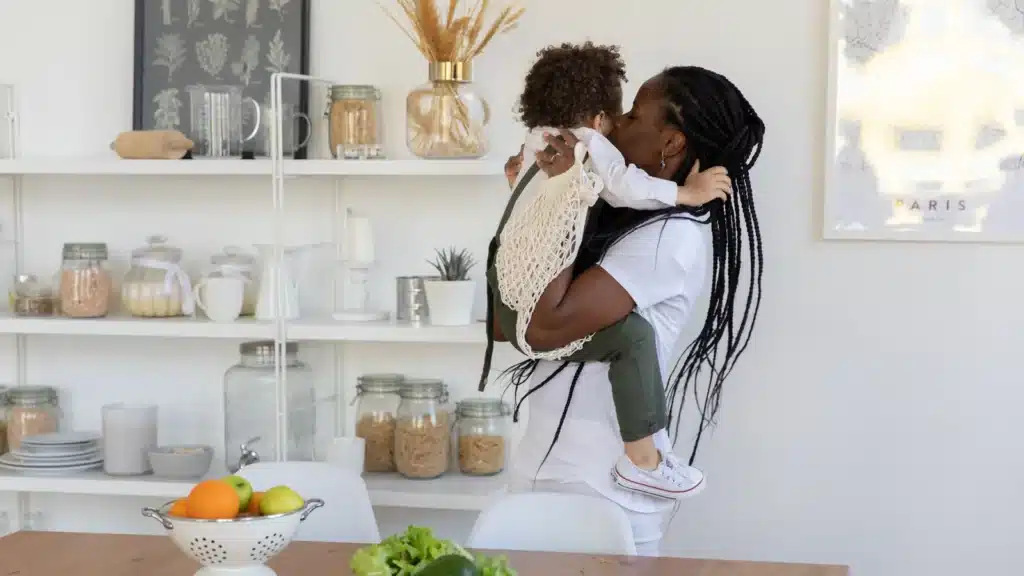 Una madre tiene in braccio un bambino nella cucina di casa